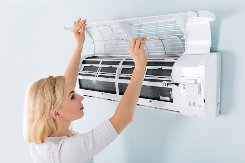 Woman performing maintenance on her home's ductless mini split. Tri Peaks Air blog image.