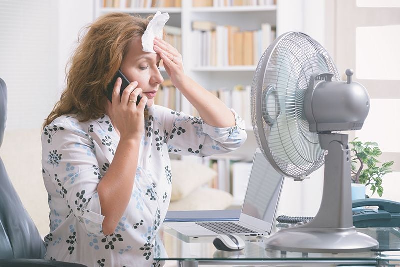 Image of person sitting in front of fan. When Do I Replace My Air Conditioner?