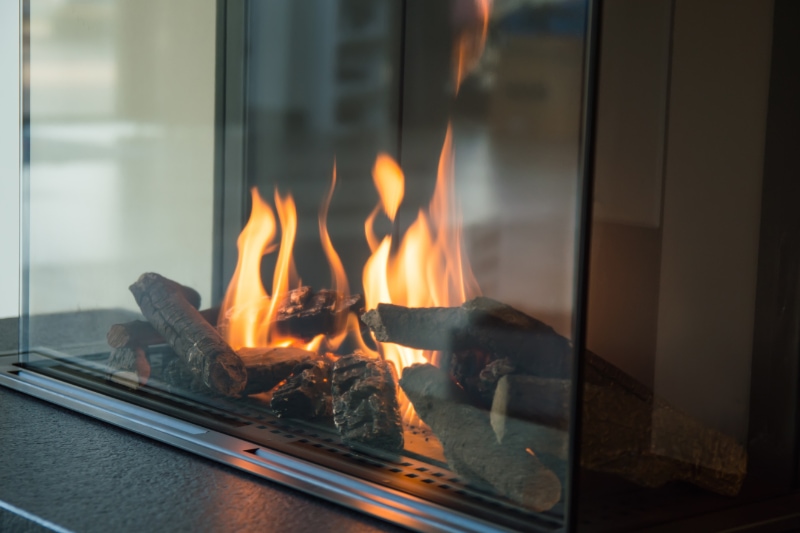 Beauty, Convenience, and Care of Gas Fireplaces. A fire burns in a glass fireplace.