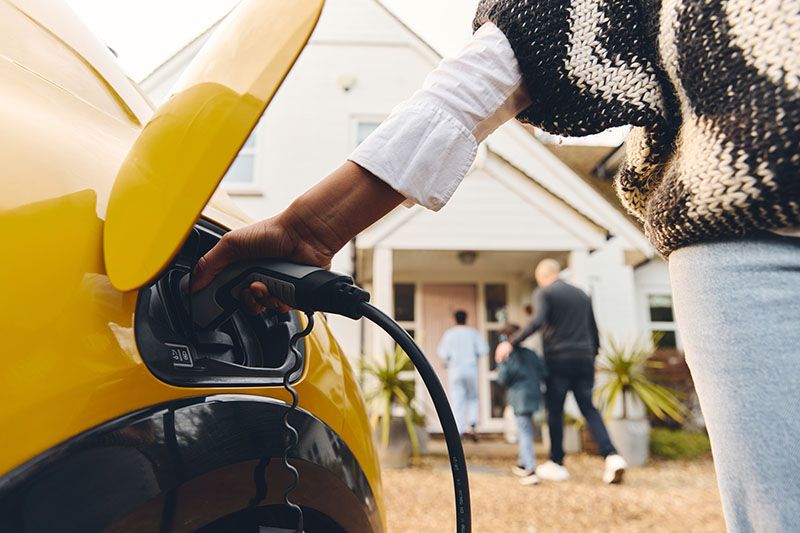 Electric Vehicle Charging Stations - Woman Charging Her Electric Vehicle.